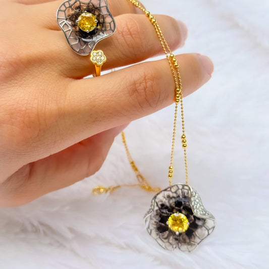 Gold necklace with a yellow gemstone pendant held by a hand on a white background