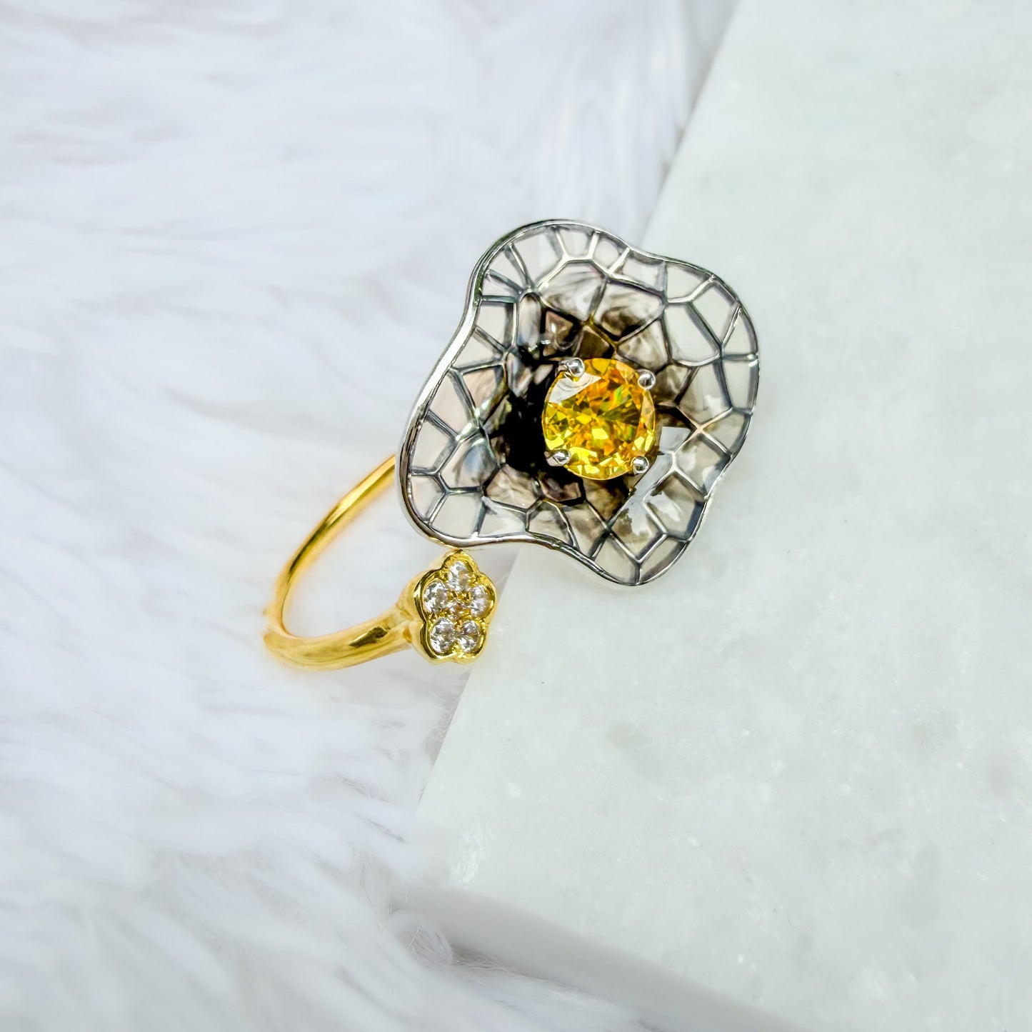 Gold ring with a yellow gemstone on a white surface