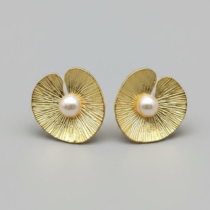 Pair of gold earrings with pearl centers on a light gray background