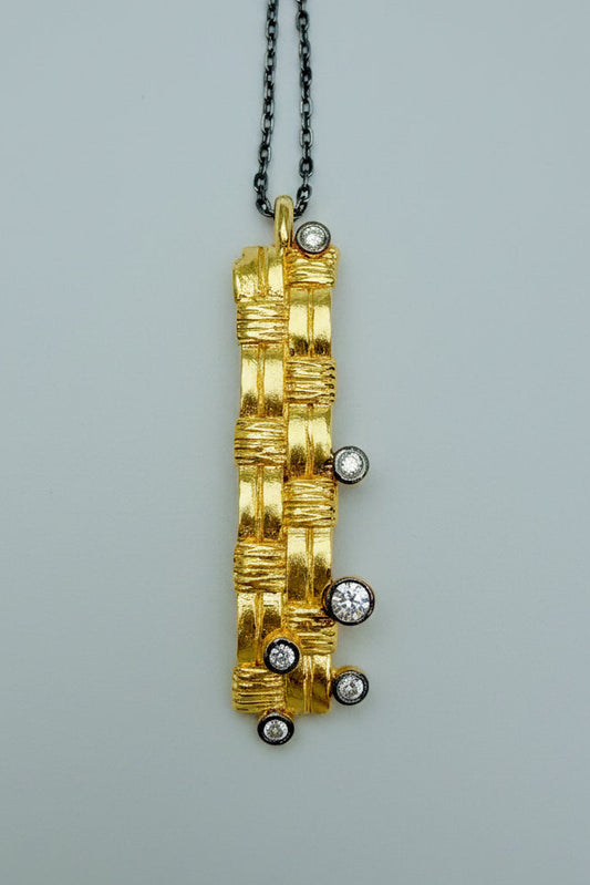 Gold pendant with embedded diamonds on a gray background