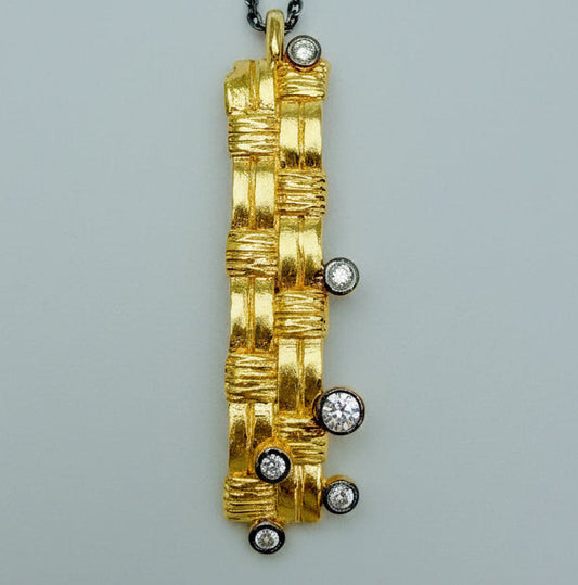 Gold pendant with embedded diamonds on a gray background