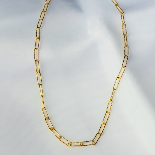 Gold chain necklace on a light gray background