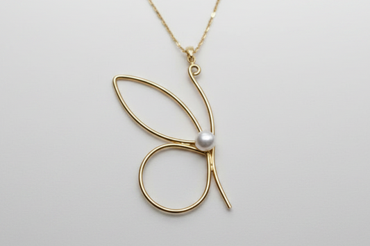 Gold butterfly necklace with a pearl on a light gray background