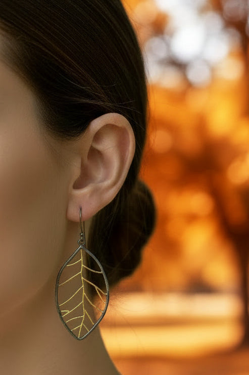 Pair of leaf-shaped earrings with gold detailing on a white background