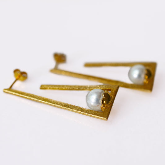 Gold earrings with pearl-like stones on a white background