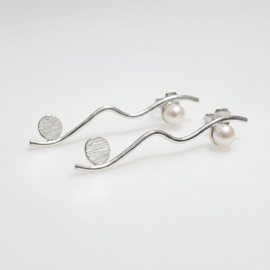 Silver earrings with pearl-like beads on a light gray background