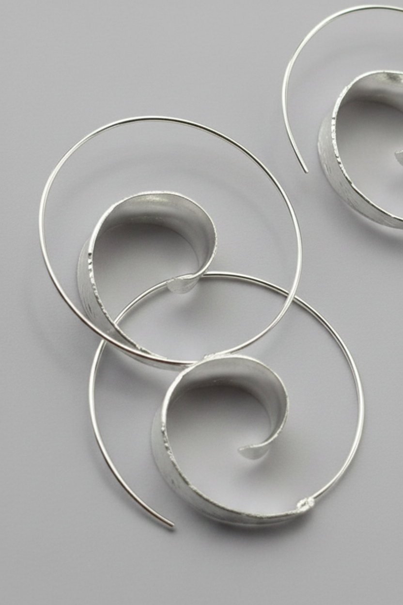 Silver spiral earrings on a gray background