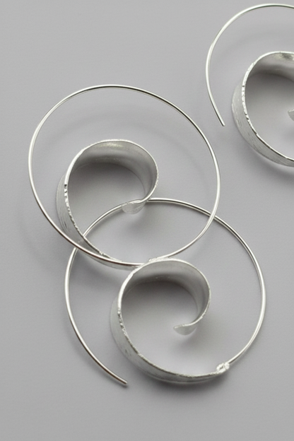 Silver spiral earrings on a gray background