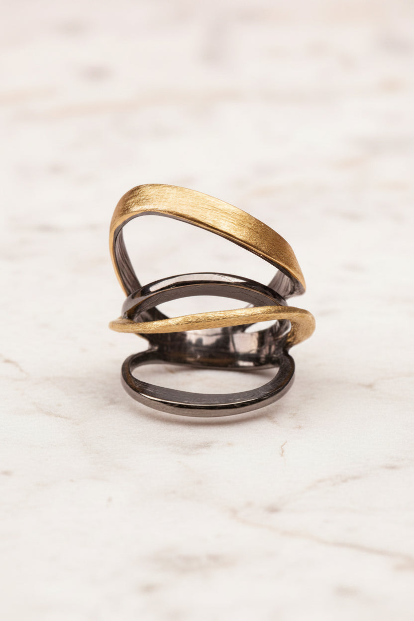 Two intertwined rings, one gold and one black, on a white background