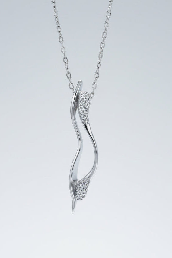 Silver pendant necklace with diamond accents on a textured white surface