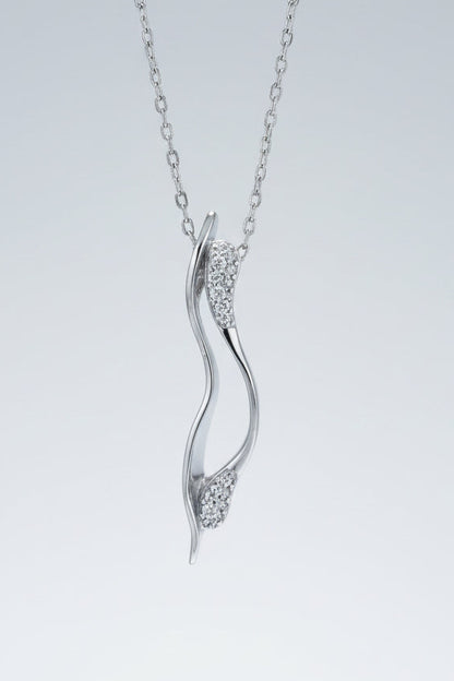 Silver pendant necklace with diamond accents on a textured white surface