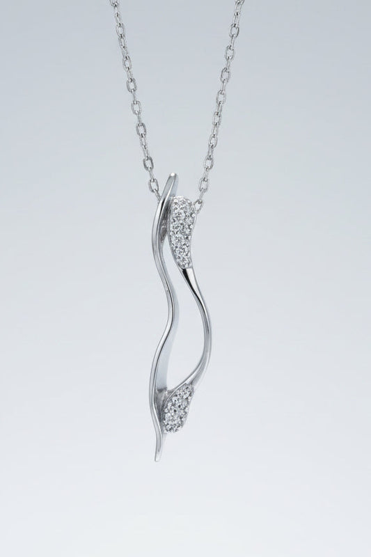 Silver pendant necklace with diamond accents on a textured white surface