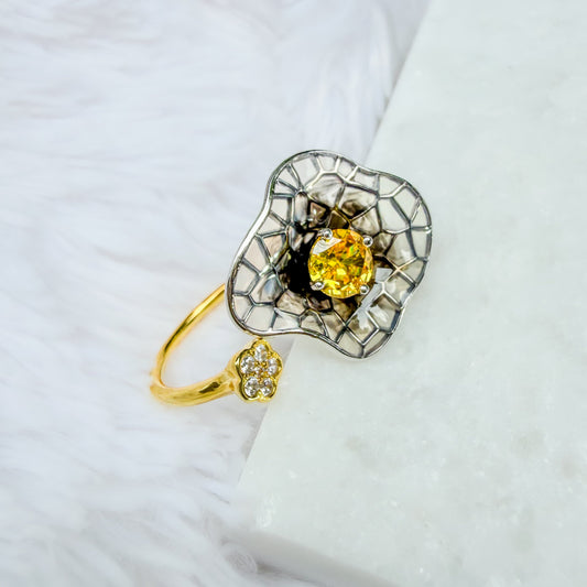 Gold ring with a yellow gemstone on a white surface