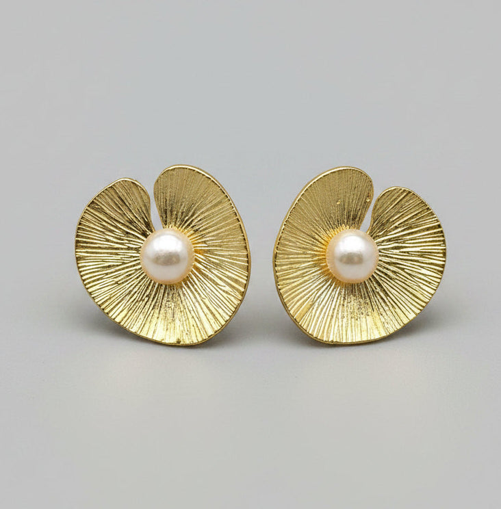 Pair of gold earrings with pearl centers on a light gray background