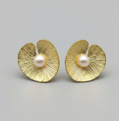 Pair of gold earrings with pearl centers on a light gray background