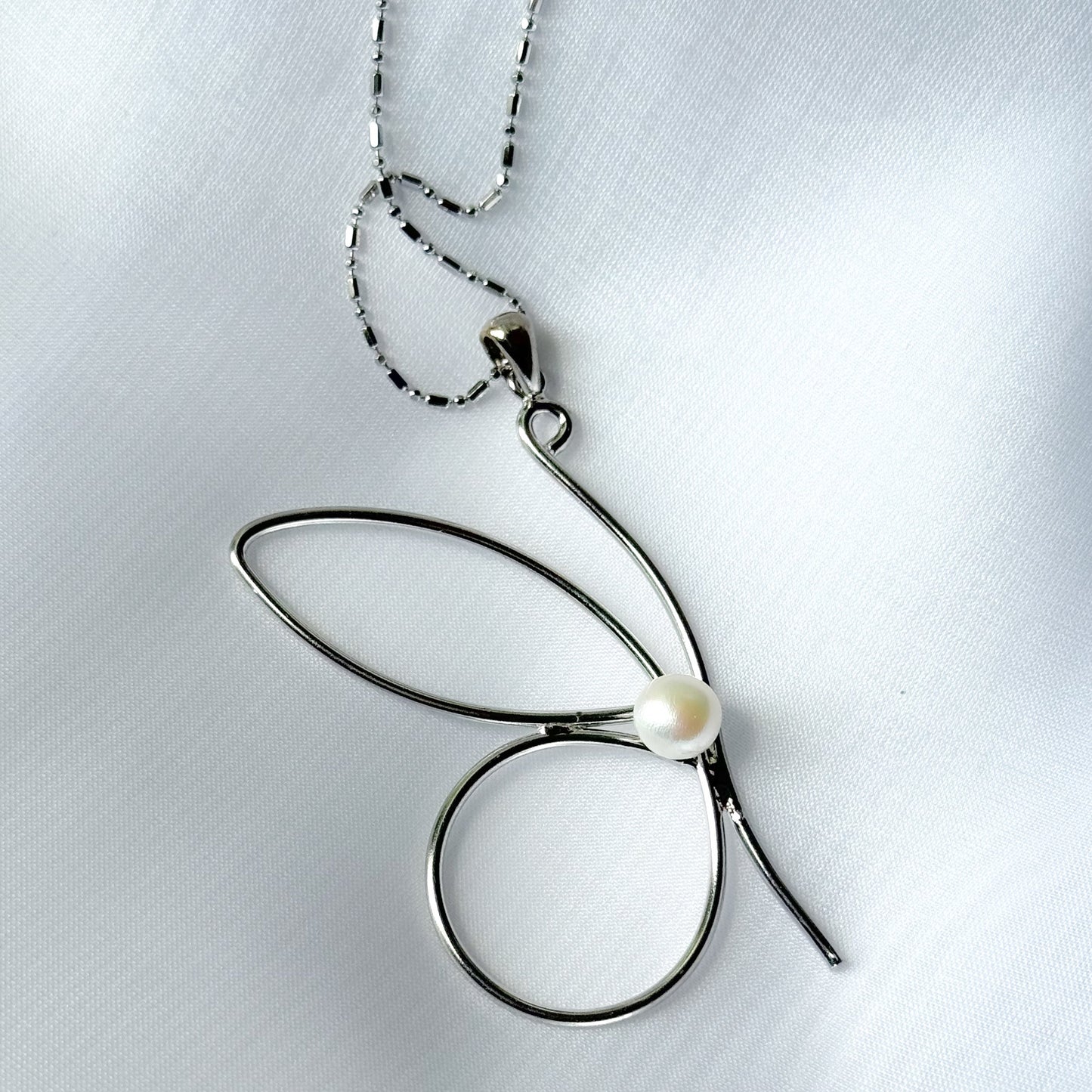 Silver butterfly pendant necklace on a light gray background