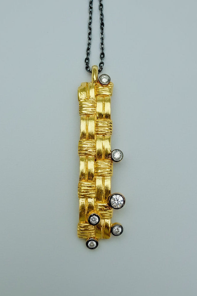 Gold pendant with embedded diamonds on a gray background