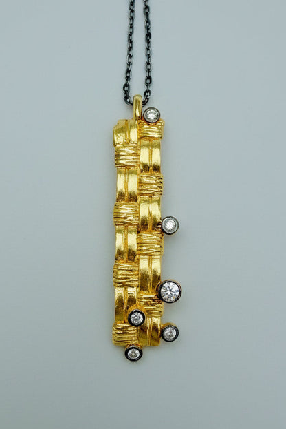 Gold pendant with embedded diamonds on a gray background