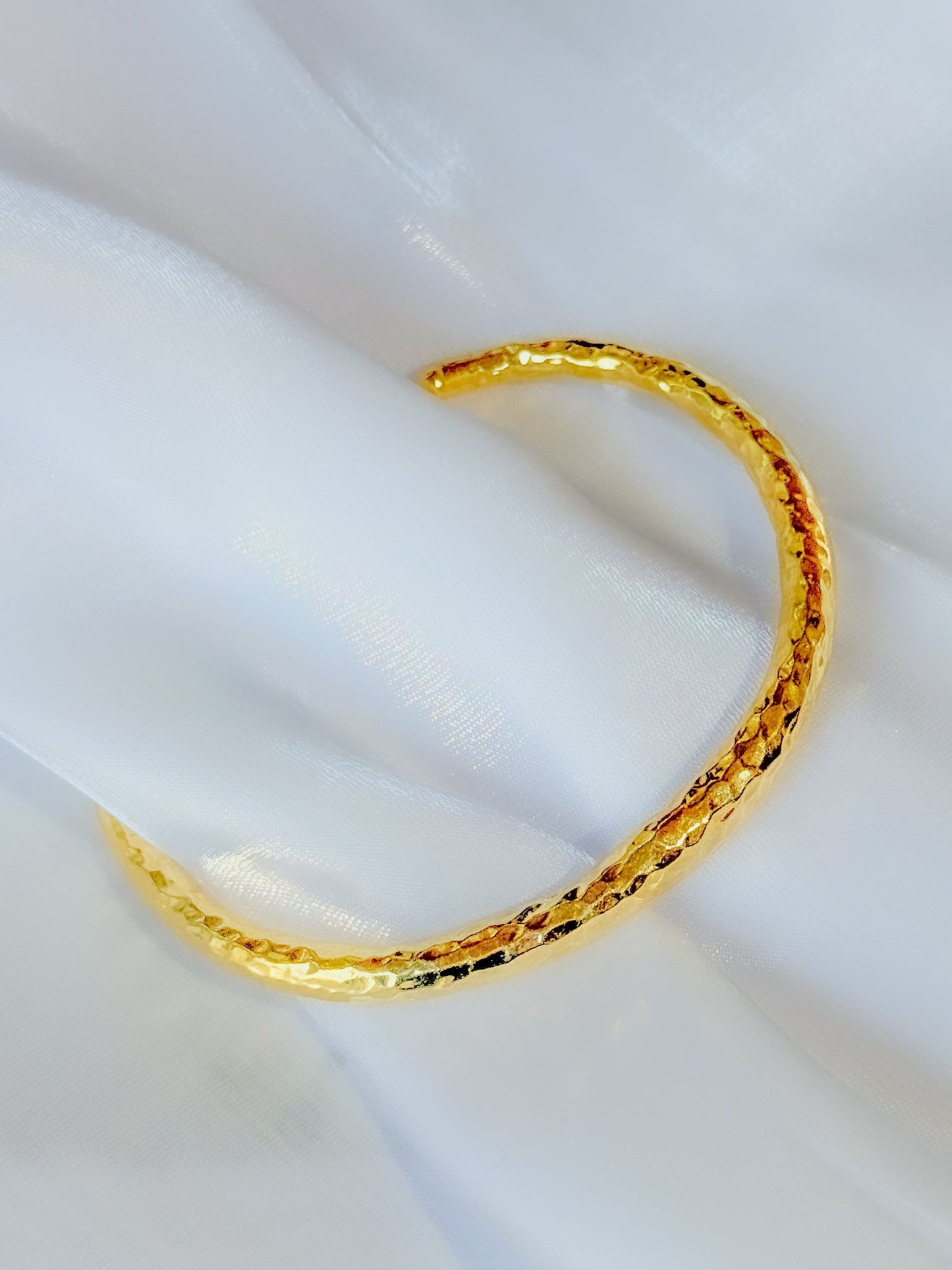 Gold bracelet on a white fabric background