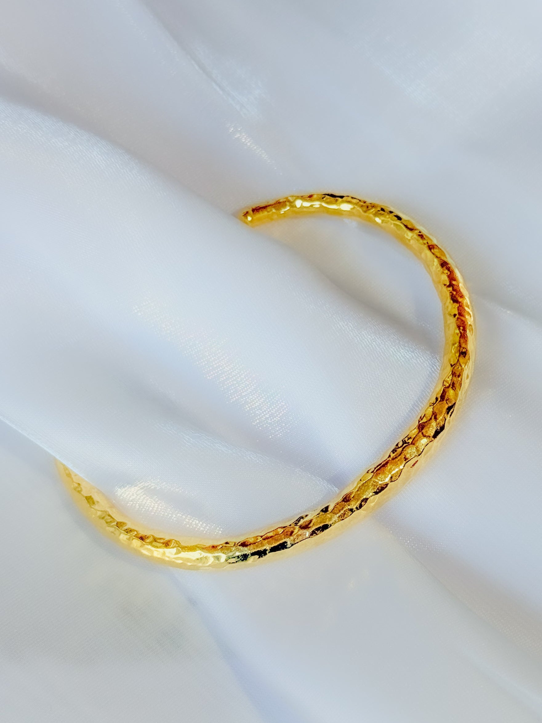 Gold bracelet on a white fabric background