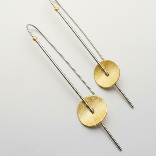 Pair of gold and silver earrings on a light gray background