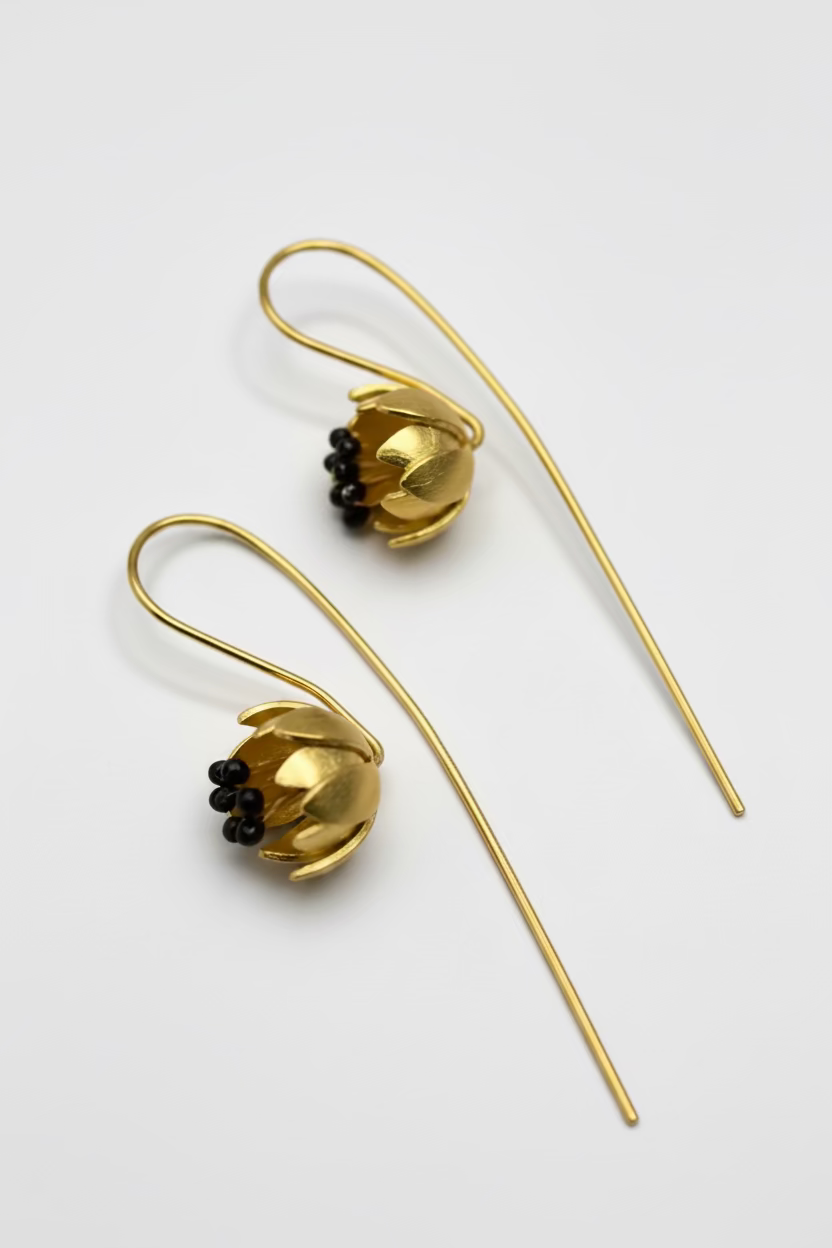 Gold earrings with a floral design on a light gray background