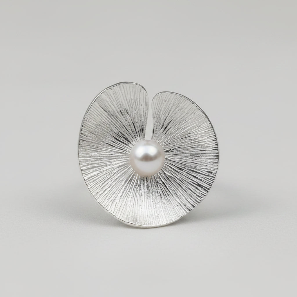 Silver earrings with textured design and pearl-like centers on a light gray background