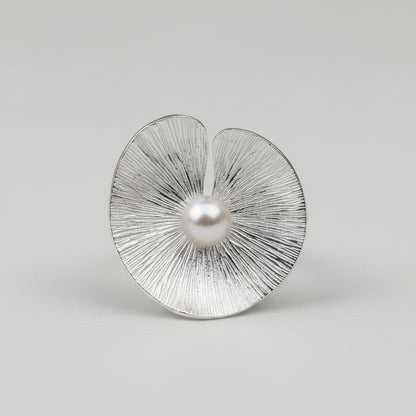 Silver earrings with textured design and pearl-like centers on a light gray background