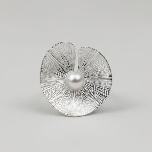 Silver earrings with textured design and pearl-like centers on a light gray background