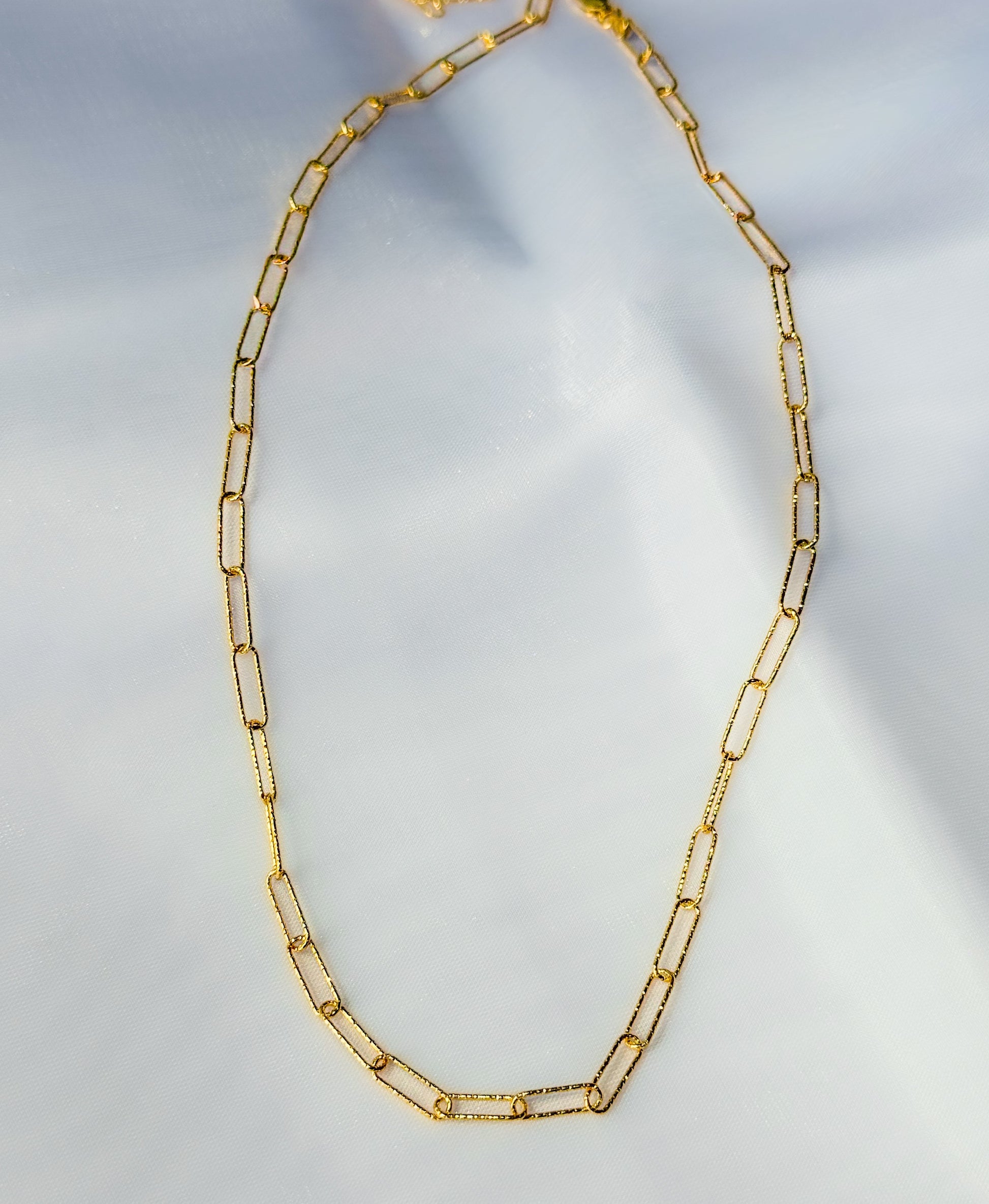 Gold chain necklace on a light gray background