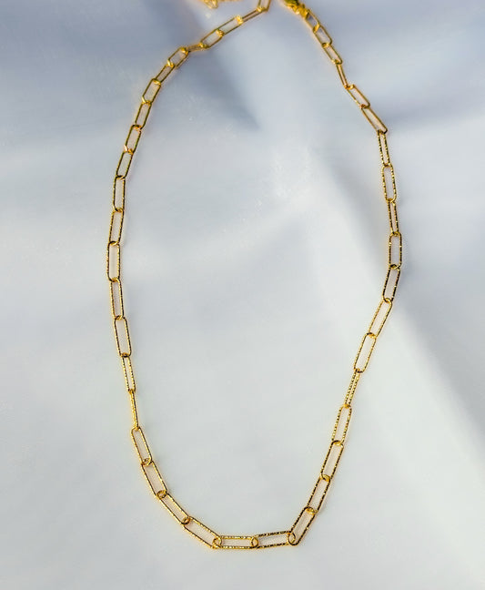 Gold chain necklace on a light gray background
