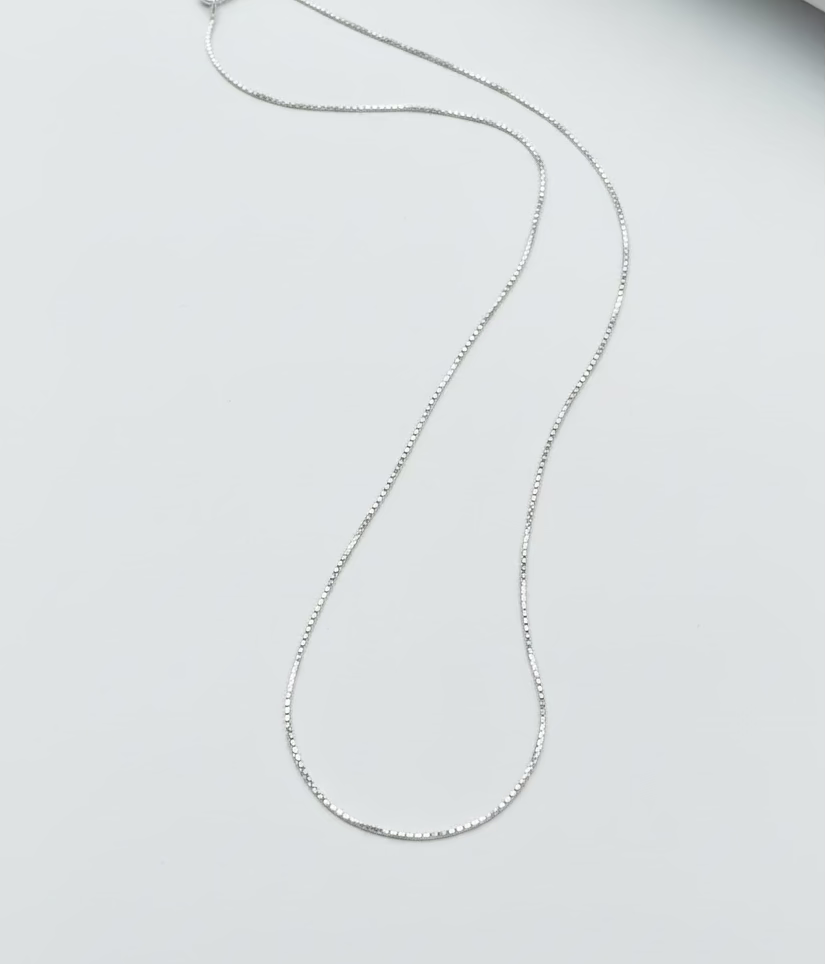 Silver necklace on a light gray surface