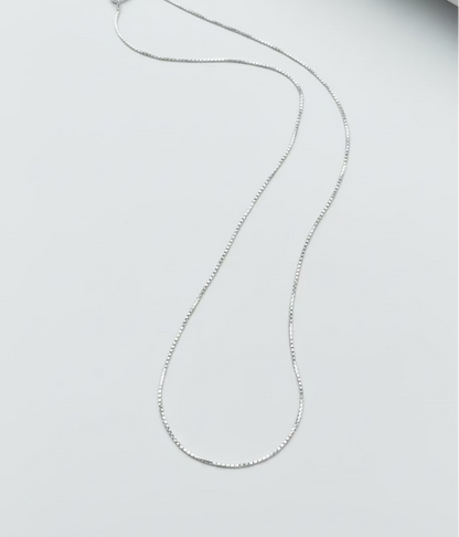 Silver necklace on a light gray surface
