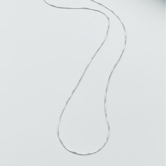 Silver necklace on a light gray surface