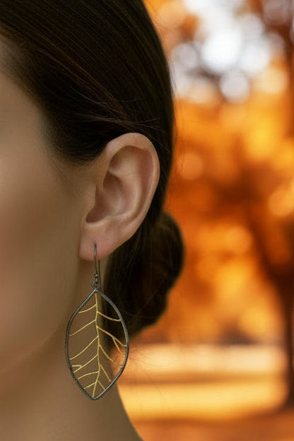 Pair of leaf-shaped earrings with gold detailing on a white background