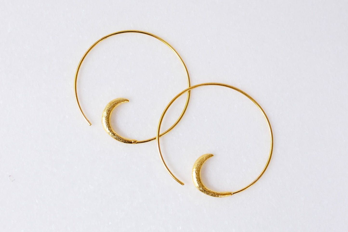 Gold hoop earrings on a light gray background