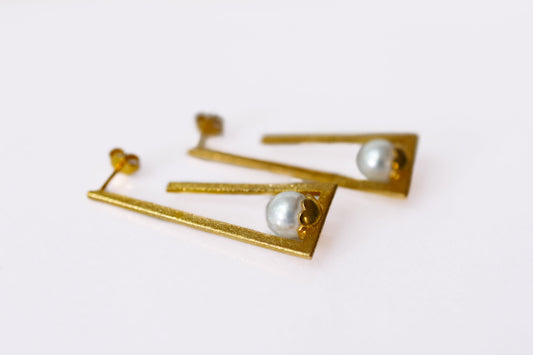 Gold earrings with pearl-like stones on a white background