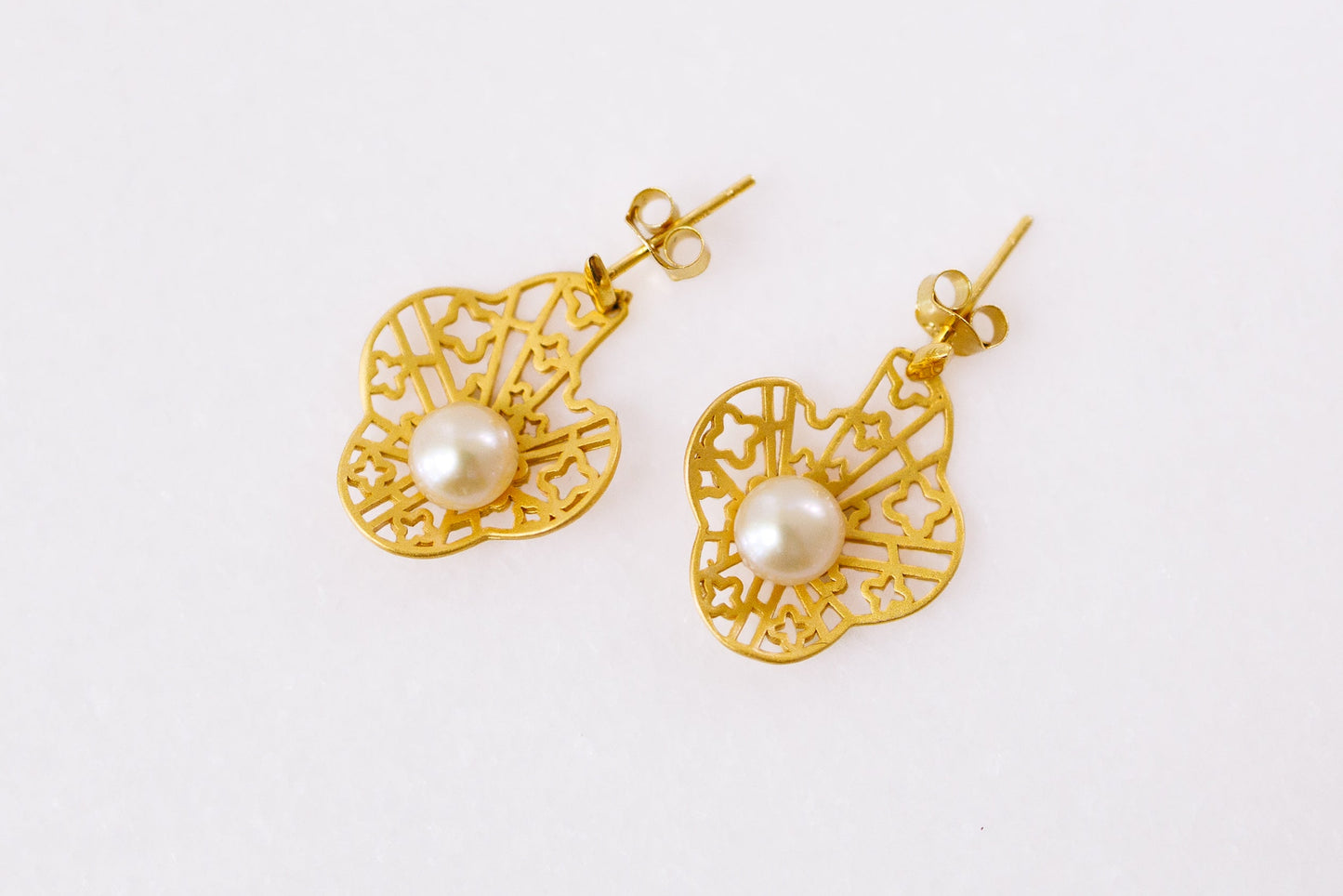 Gold earrings with pearl centers on a white background